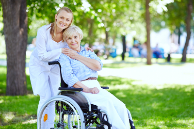 elderly woman in a wheelchair with her caregiver early morning in the park